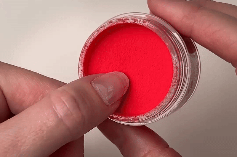 GIF von einem Daumen der in das rote Dipping Powder eingetaucht wird.
