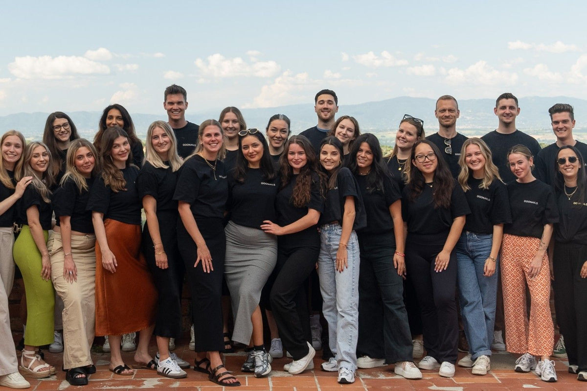 Gruppenbild des Doonails Teams, lächelnd und in lockerer Pose. Alle tragen ein schwarzes T-Shirt. 