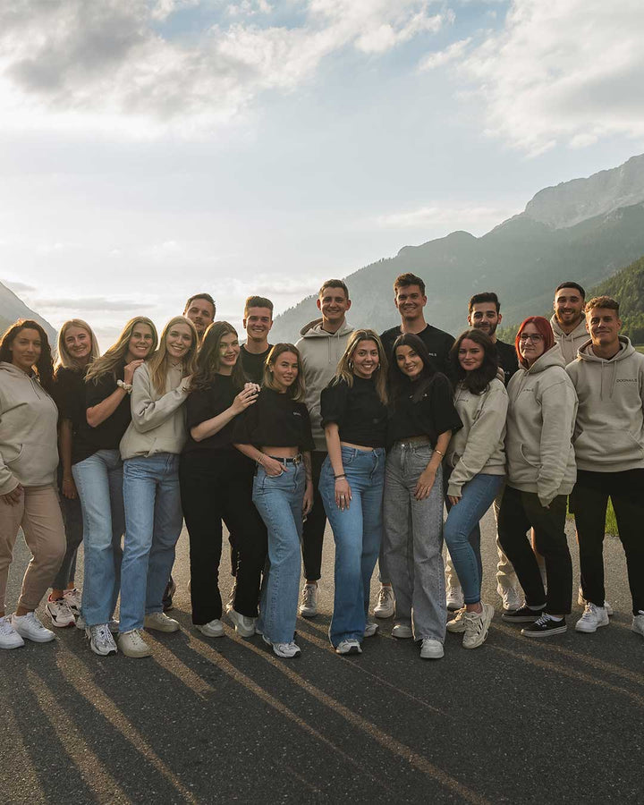 Gruppenfoto des Doonails Teams in den Bergen. Das Team hat schwarze und beige Oberteile an. 