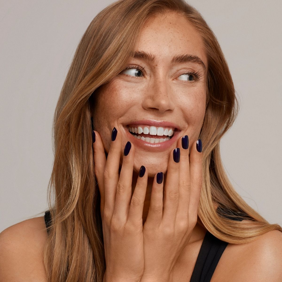 Lächelnde Frau mit rötlichen Haaren und dunklen Fingernägeln