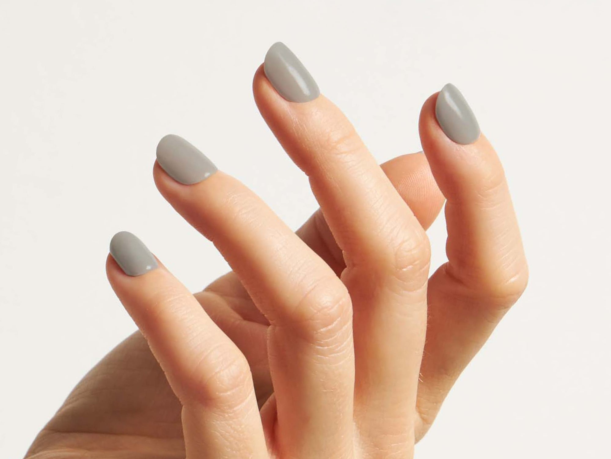 Hand mit grauen Dipping Powder Nägel vor weißem Hintergrund.