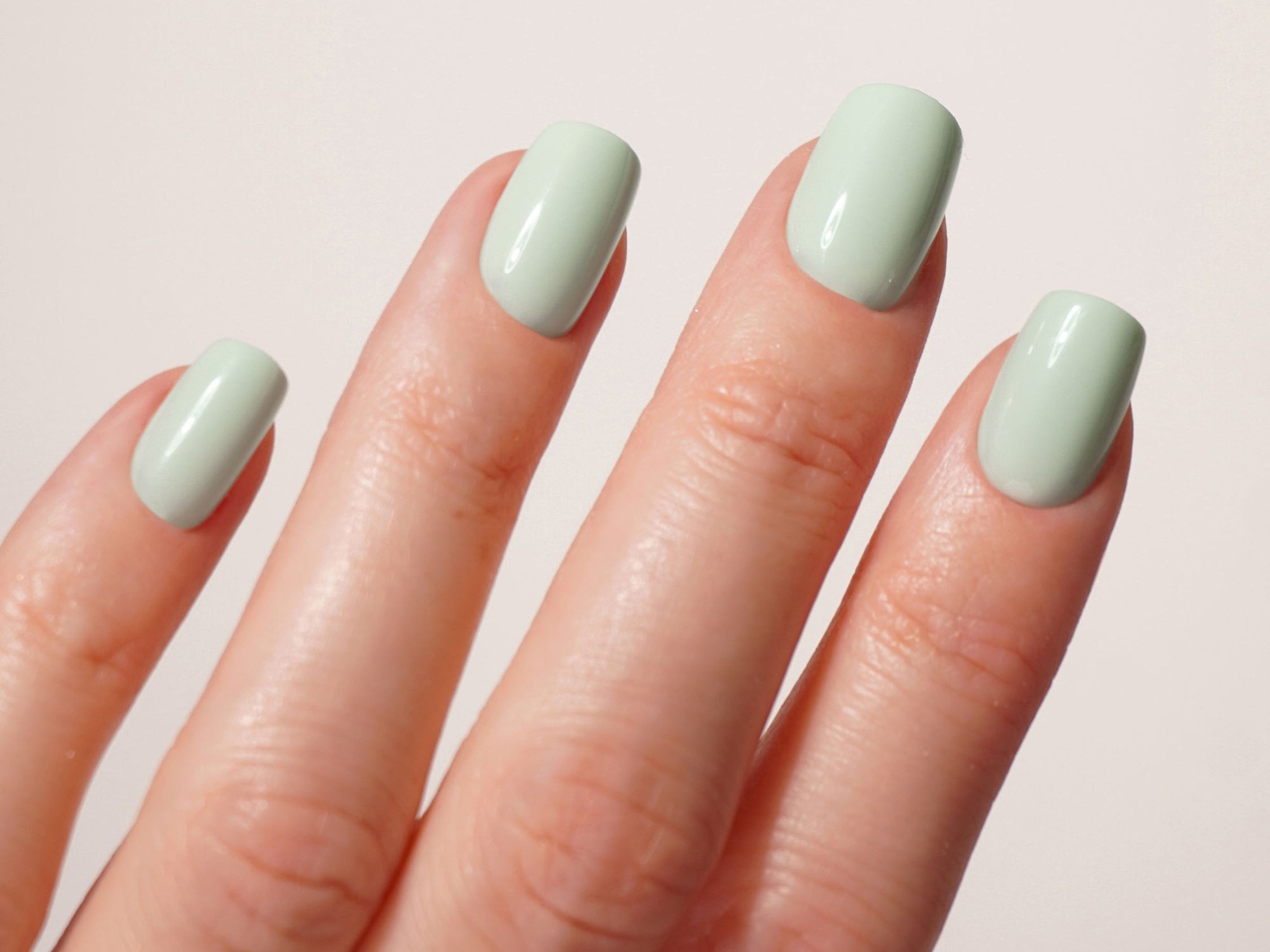 Hand mit mintgrünen Square Press Ons vor weißem Hintergrund.