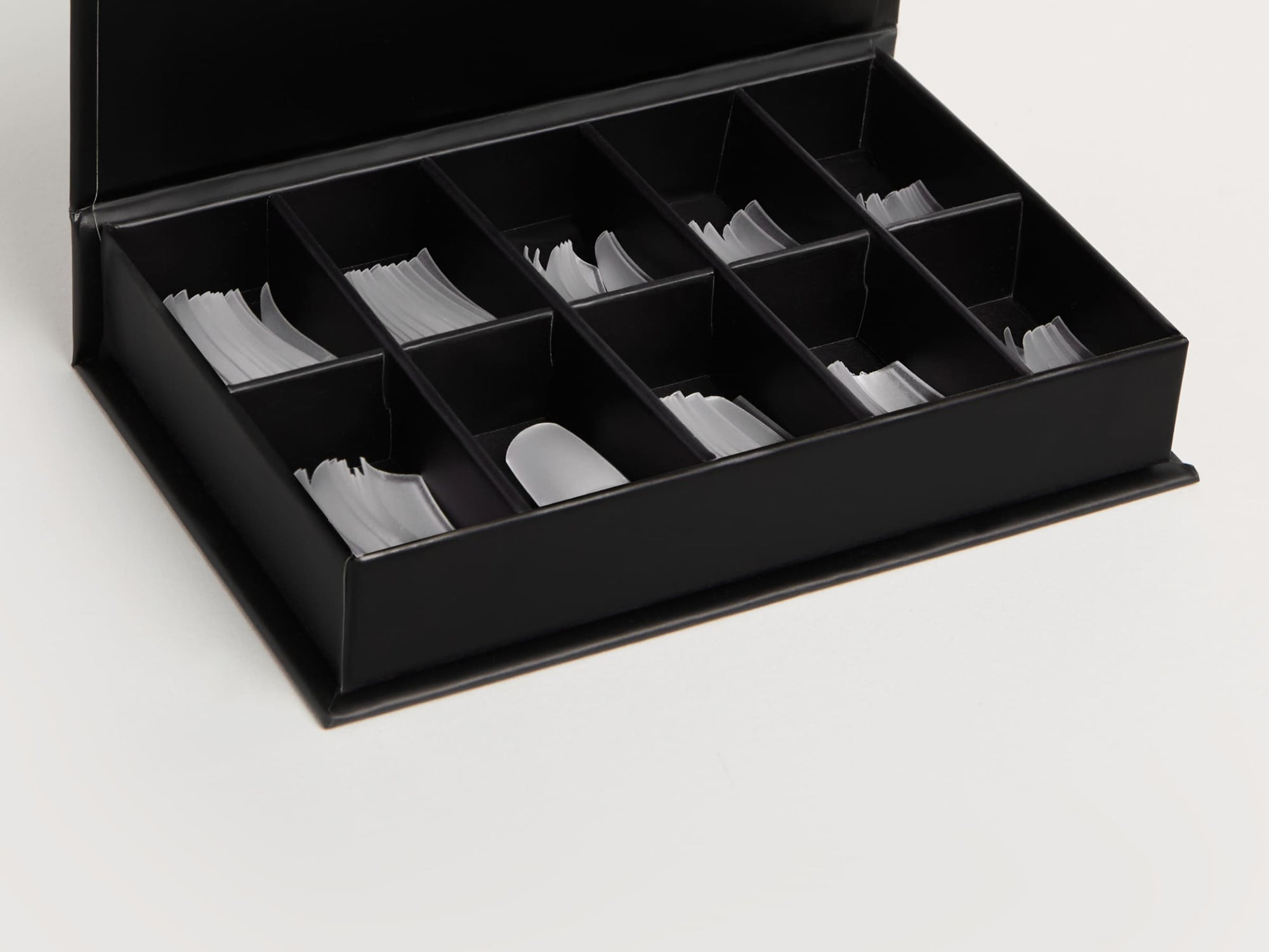 Aufgeklappte Box mit Nagelverlängerungs-Tips auf weißem Hintergrund.