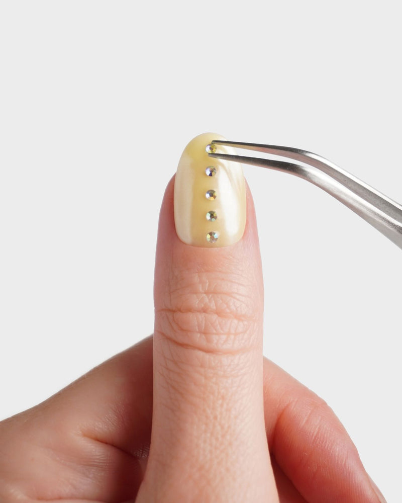 Nailart Pinzette beim Platzieren eines Strasssteines auf den Nagel