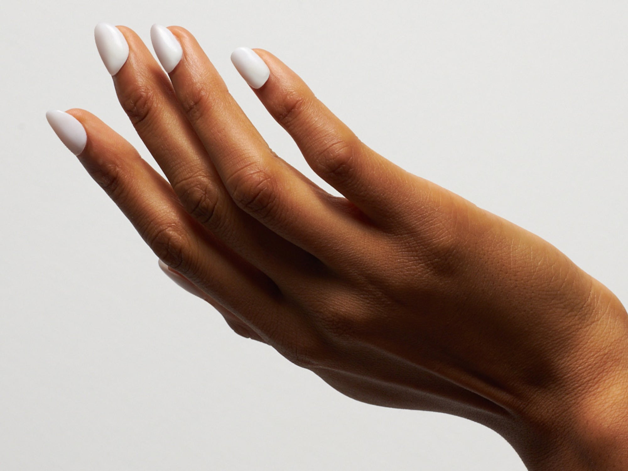 Hand mit weißen Dipping Powder Nägel vor weißem Hintergrund.