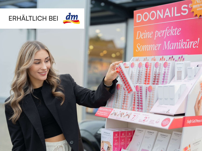 Lächelnde Frau, die eine Press On Packung vom Aufsteller nimmt